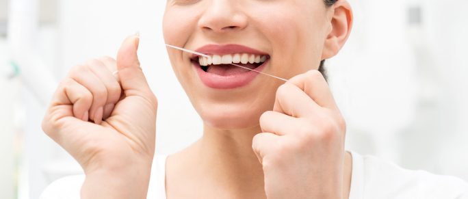 Woman using dental floss for cleaning her teeth