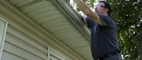 a man cleaning gutters on a house