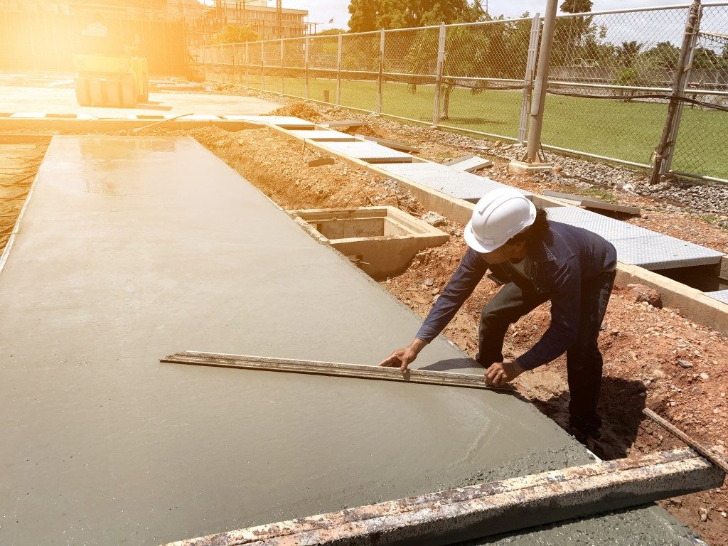 Construction worker making the soft concrete flat