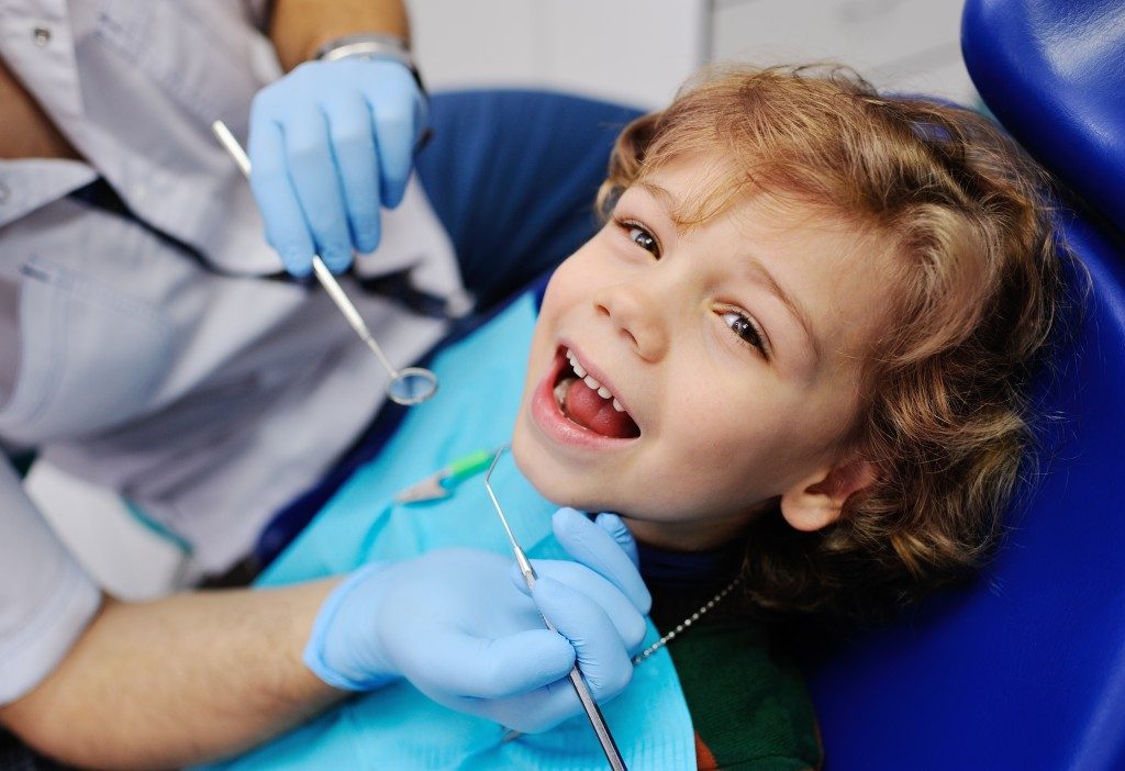 boy smiling while on a dentist chair