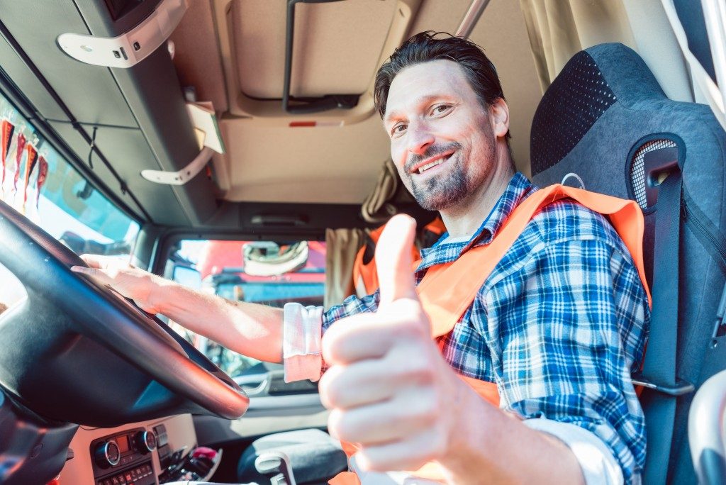 Truck driver man sitting in cabin giving thumbs-up 